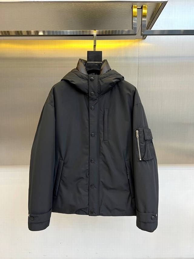 Prada 普拉、男士织物面料连帽羽绒夹克外套。 这款现代运动风羽绒夹克采用织物面料和Oversize宽大廓形，配有风帽。搭配实用性元素和精致细节，以极简主义设