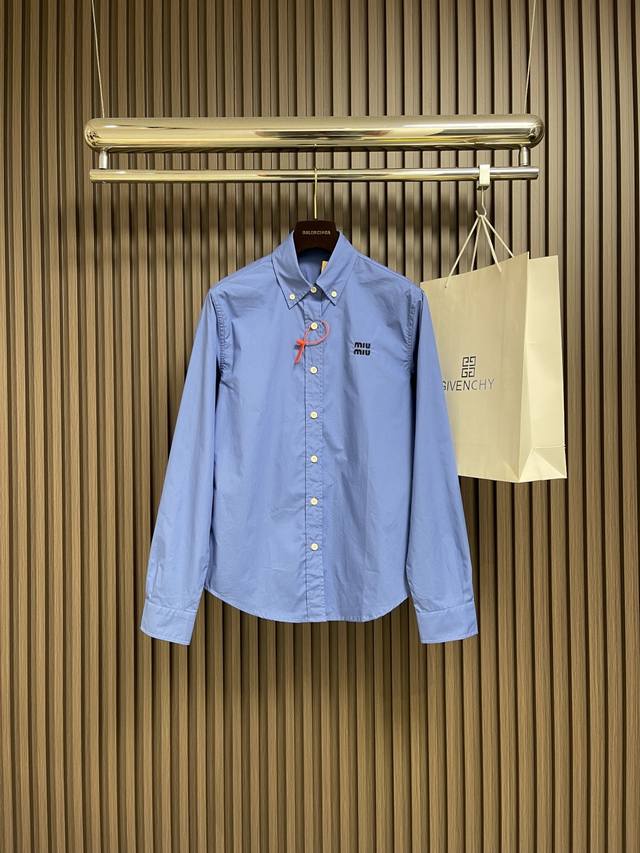Miumiu 徽标刺绣衬衫，定制天丝棉交织纱衬衫料 柔滑细腻 舒适贴肤 一抹靛蓝晕染在衬衫之上 高贵而优雅精致Miumiu徽标刺绣在左胸处翩翩起舞 增添品牌辨识