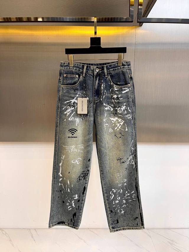 Balenciaga巴黎世家、2025秋冬新款以经典牛仔蓝为画布，白色喷墨涂鸦如数字信号般肆意流淌。标志性Wifi符号跃然裤身，宣告街头与虚拟世界的无缝对接。