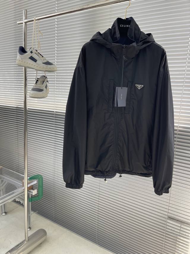 Prad 再生尼龙双面穿夹克 选用品牌标志性的再生尼龙面料，与传统尼龙性能相当，具备高强度，抗撕裂，耐磨损等特性。其质地轻盈，同时又具备防水功能适合多场景需求。