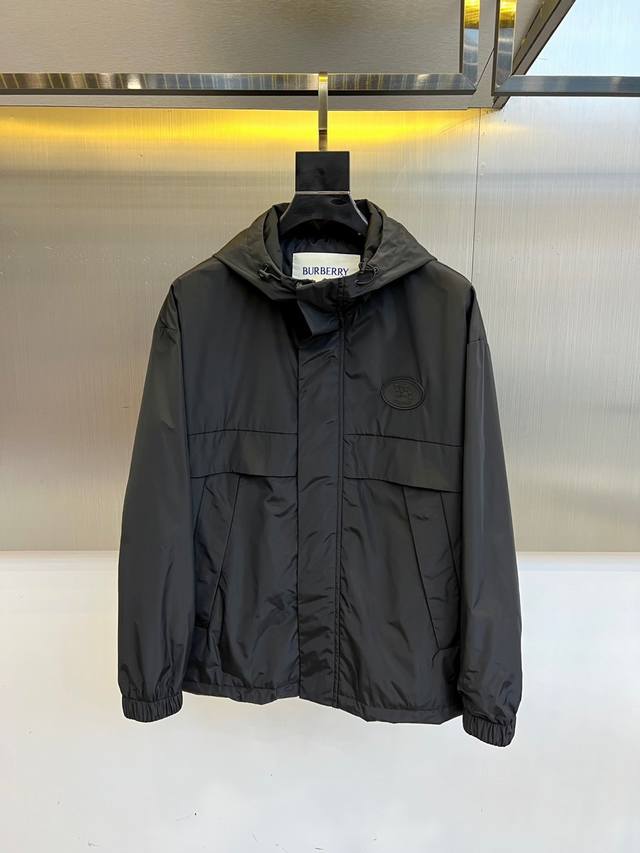 Burbery 巴宝、25S秋冬新品发售骑士徽章连帽夹克外套。 深邃黑色棉质混纺面料，左胸压印经典骑士徽章彰显英伦血统。可调节连帽设计搭配隐藏式抽绳，内衬紫色B