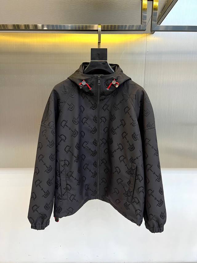 Gucc古驰、 暗纹机能连帽夹克 哑光黑面料铺满立体暗纹图腾，高级聚酯纤维打造防水机能属性。全拉链设计搭配醒目红色抽绳，撞色调节扣点亮整体造型。弹性袖口与宽松下