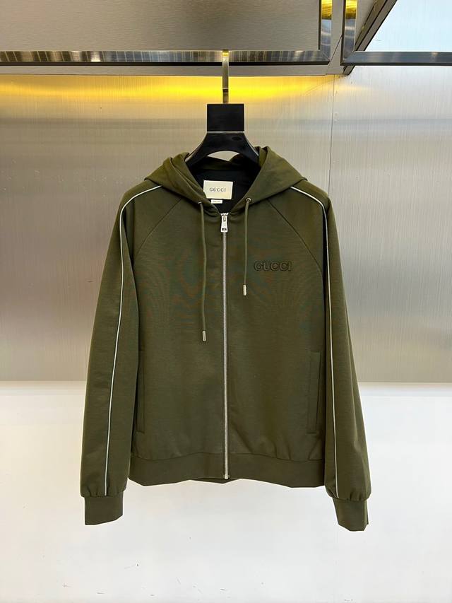 Gucc古驰、25Fw军绿连帽拉链外套，采用挺括棉质混纺面料，立体剪裁搭配抽绳连帽设计。胸前经典双G标识，袖口与衣襟缀以白色线条，兼具运动感与高级时尚格调。48