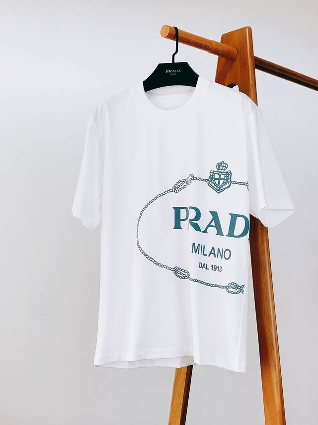 Prada 普拉达 2025Ss春夏新品 休闲印花T恤。简约大气，正面标志性“Prad* Milano Dal 1913”印花，搭配链条与徽章元素，复古又具辨识