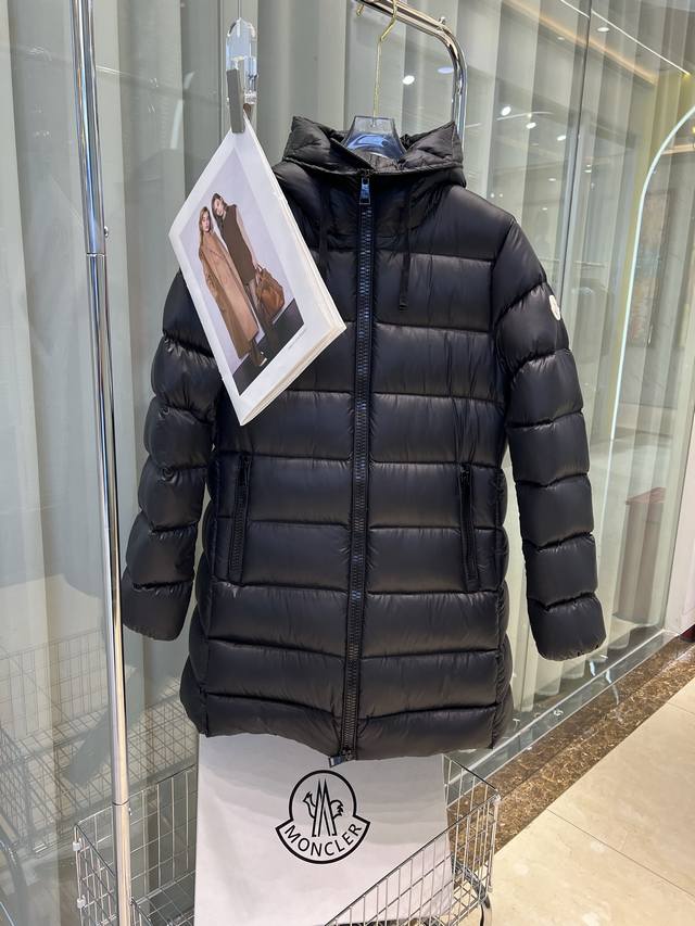 Moncler蒙口经典娃娃款，Moncler蒙口Suyen女士长款羽绒服夹克。这款夹克适用于都市的常备考究冬季单品，采用闪亮漆面尼龙制成。长方格绗缝彰显充满女性