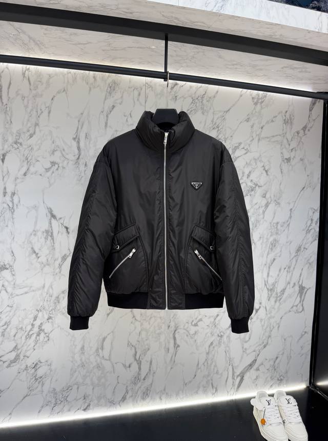 放货价 prada普拉达新款提花尼龙羽绒服金属小标羽绒服。采用Re-Nylon再生尼龙打造，现代设计风格,和廓形相得益彰，采用给予更温暖防护标志性的涂珐琅金属三