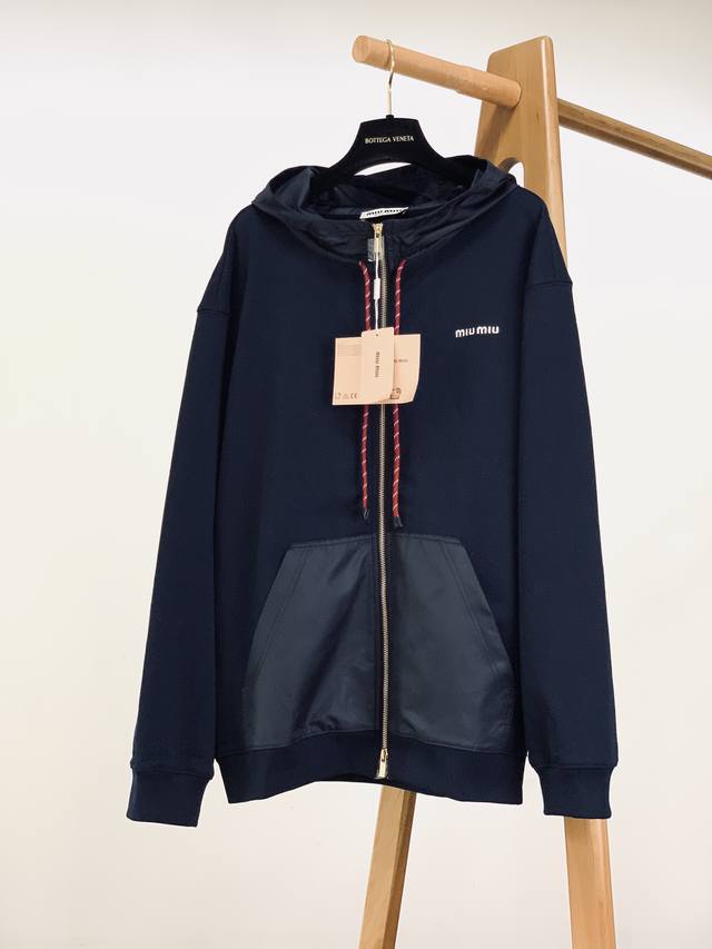 Miumiu 缪缪 2025Fw早秋新品 连帽拉链卫衣外套，解锁复古运动风的奢潮格调。 藏青主调搭配哑光质感的拼接面料，加上红白织带抽绳的点睛之笔，复古运动感拉
