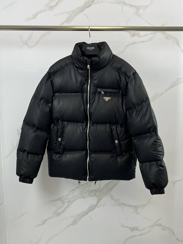 特级羽绒prada 普拉达 科技皮膜羽绒夹克 压胶版本 .此款衣服面料为24最新科技面料，保持了羊皮的柔软细腻质感，比起常规皮质羽绒服更佳轻便,易保养.充绒用的