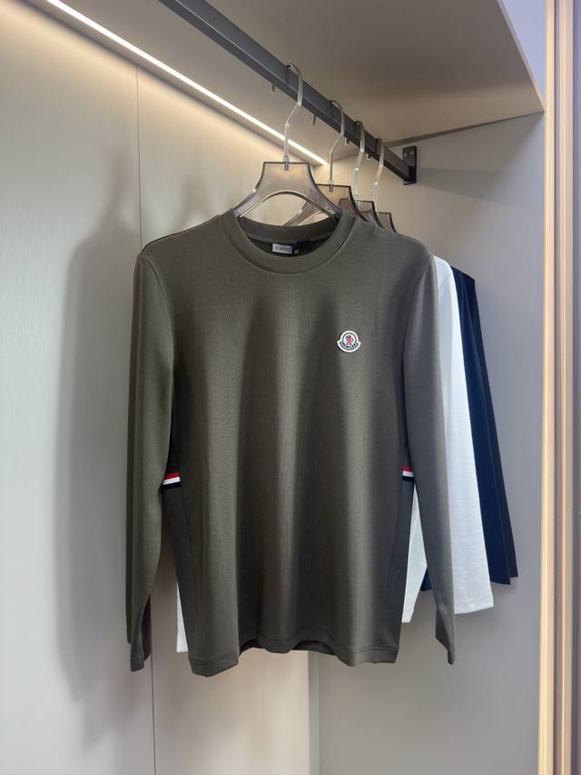 Moncler2025新款长袖打底衫 Moncler这款打底衫款式采用基础圆领长袖款式，简约基础款式，侧边拼接设计，配上品牌经典颜色织带，增添细节层次感；胸前有