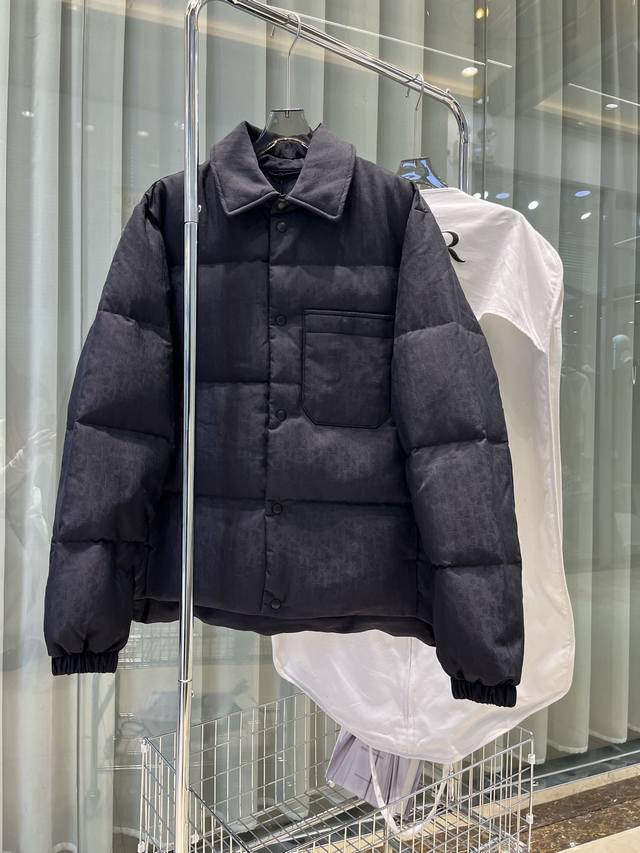 25年这款夹克突显 Dior 经典的 Oblique 印花。采用黑色科技提花面料精心制作，背面饰以 Dior 橡胶补丁，搭配衬衫领彰显个性。通体饰以同色调印花，