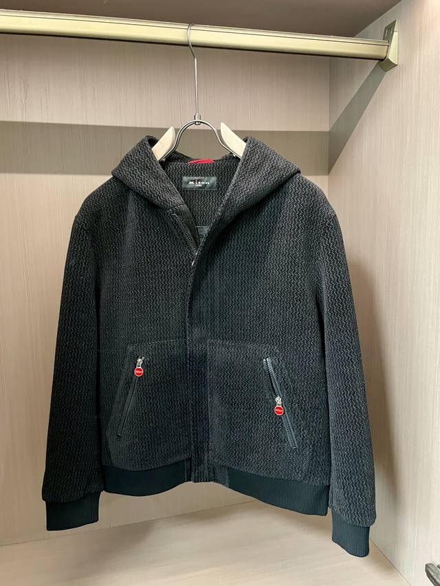 Kiton 2025秋冬新品 男女同款外套 特殊的纹理面料自带细腻肌理，深灰色调低调又有质感；连帽设计休闲随性，胸前的拉链口袋搭配红色饰扣，在简约中玩转出细节巧