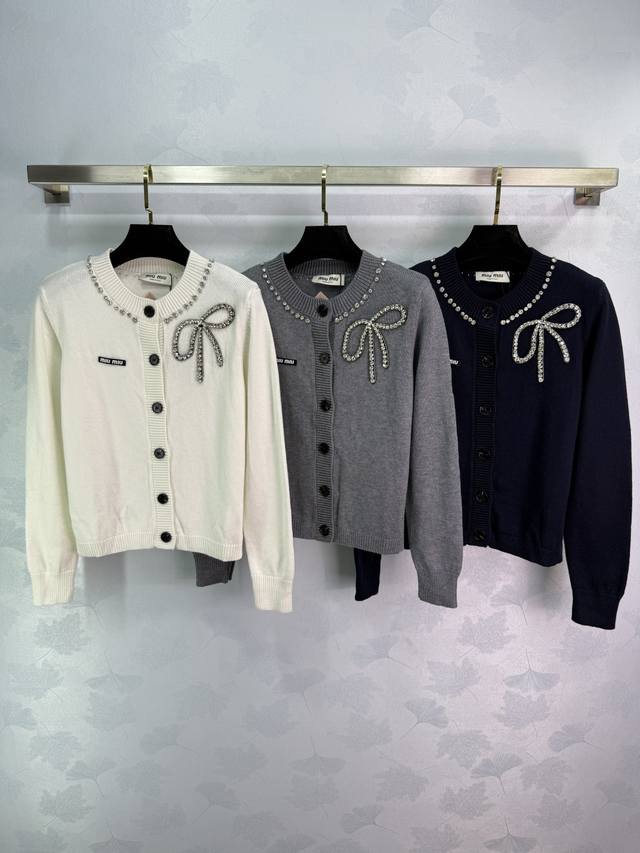 Miu*25早秋新款蝴蝶结针织开衫 精致手工钉珠蝴蝶结设计 搭配黑色纽扣 圆领开衫款式 羊毛混纺面料 柔软舒适 针织工艺精湛 修身显瘦版型 春秋百搭 四季单穿叠