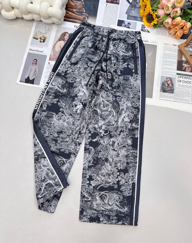 Dior 重工动物丛林提花侧边字母老花阔腿裤 这款长裤彰显经典的蓝色 Oblique 印花 侧面饰以对比鲜明的“Christian D*Or”标志条形图案 打造