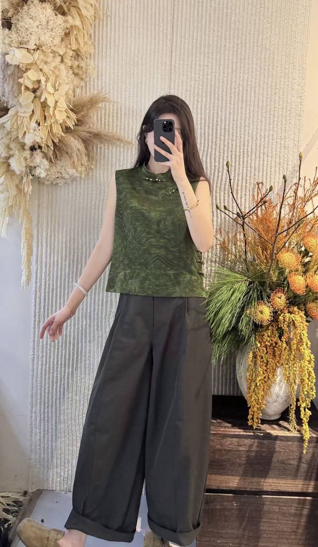 禅意墨绿提花马甲，以高级油丝为载体，墨绿底色晕染着精致提花，似古画纹理般细腻有韵。立领配复古盘扣，将中式雅致融得利落大气；无袖剪裁更显简约干练，弱化了“中式”的