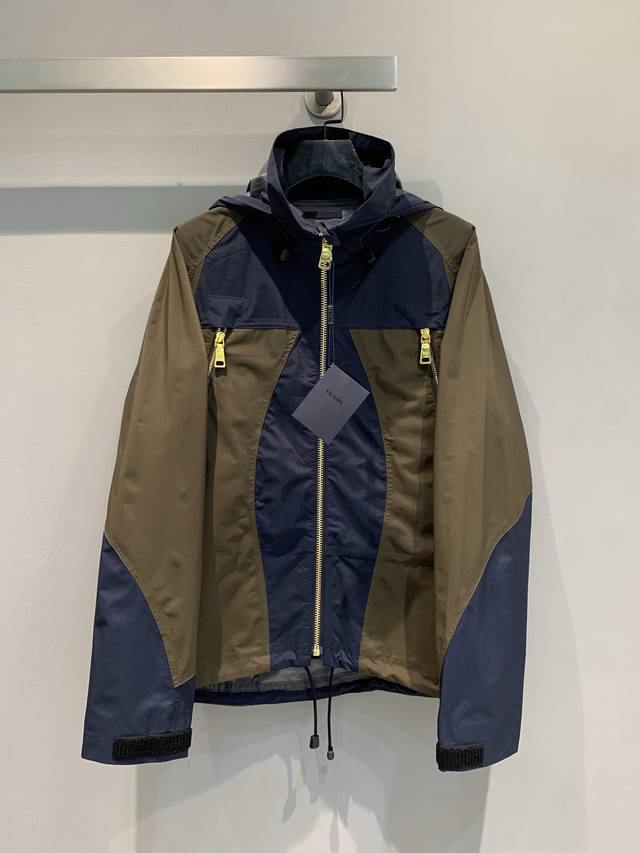 Y版开发 prad*2025早秋新款复古时髦撞色连帽冲锋衣。精选高品质面料，兼具防风防水性能，蓝棕撞色设计大胆又和谐，打破单调，尽显独特品味。连帽与拉链细节，实