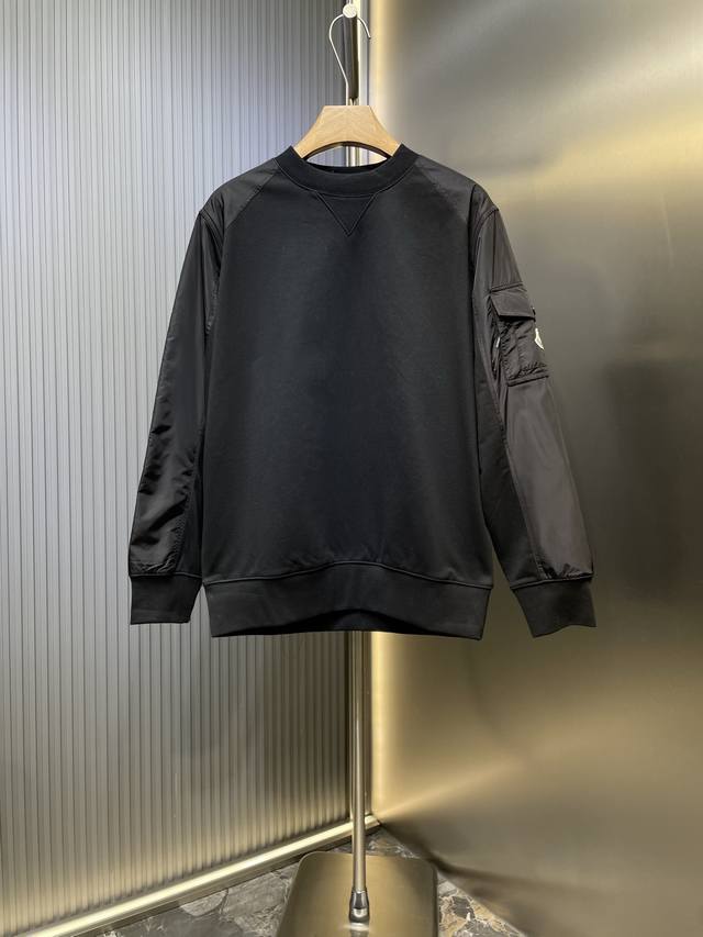 Moncler 标识贴袋拼接卫衣 定制柔绒棉质混纺暖芯料 以及臻韧尼龙高密织造料 光滑细腻 舒适贴肤 以一抹深邃黑幕为底 胸前悄然绘就一方三角形天地 标志性Mo