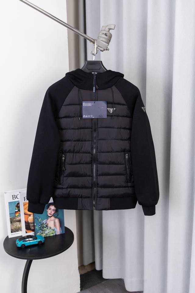 款号S033 普拉达经典三角徽标醒目嵌于前胸，是百年奢品身份的硬核标识；连帽版型自带休闲感，抽绳设计可自由调节，寒风里也能护住脖颈暖意，让 “辨识度” 与 “实