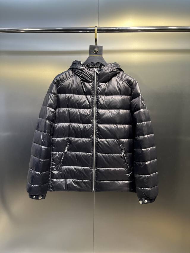 Prada连帽压纹垫肩测纹羽绒轻薄羽绒外套 这款羽绒外套采用现代廓形，融合了运动风格与时尚细节。休闲设计点缀涂珐琅三角形金属徽标，搭配技巧连帽和90绒填充物填充