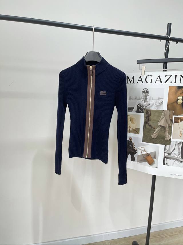 M藏蓝坑条立领拼皮拉链开衫 ，面料：绵羊毛 颜色：藏蓝 Miu这款针织拉链开衫 藏蓝色羊毛皮包边，质感超细腻 正面拉链皮革“Miu”标志 复古优雅感拉满计 修身