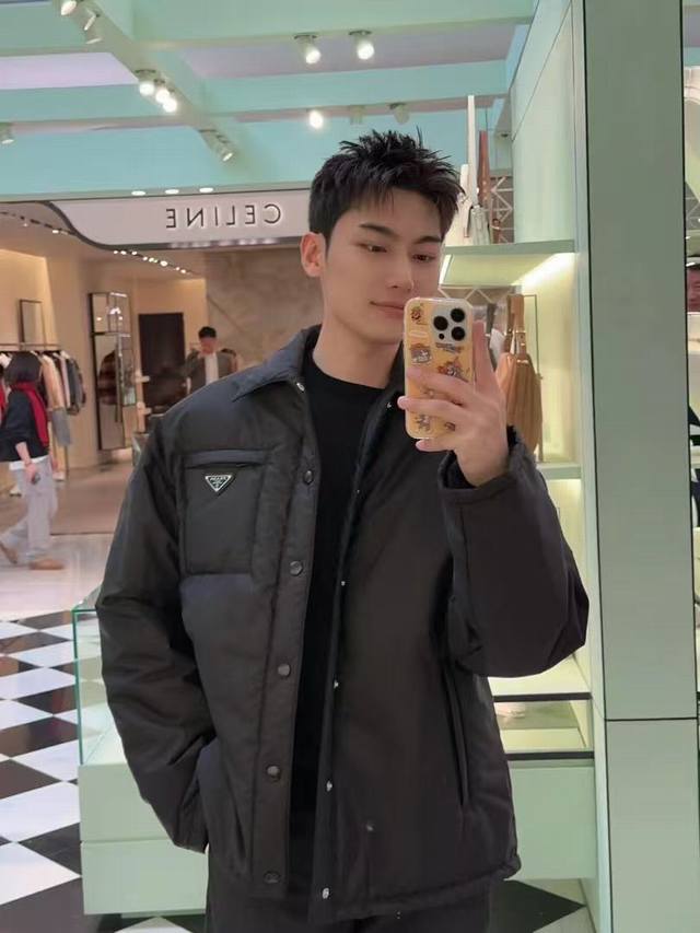 Prada再生尼龙轻薄棉服 面料选择： 选用品牌标志性的再生尼龙面料，与传统尼龙性能相当，具备高强度，抗撕裂，耐磨损等特性。其质地轻盈，同时又具备防水功能适合多