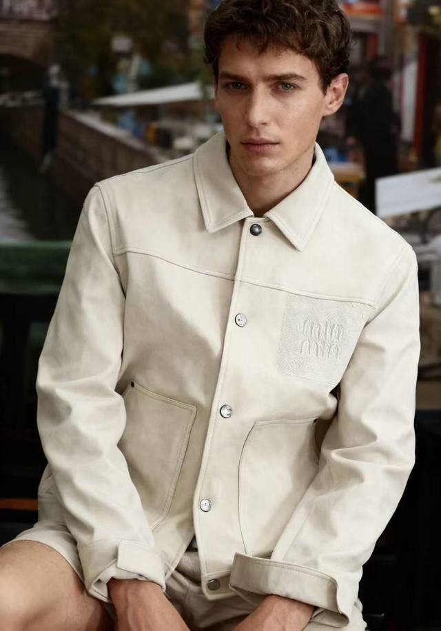 Miumiu. 2025秋季新款！时尚男款翻领夹克采用聚酯纤维面料！配带有金属纽扣，左胸有品牌标识刺绣口袋，风格兼具复古与现代感。这类带有品牌细节的设计既保留了