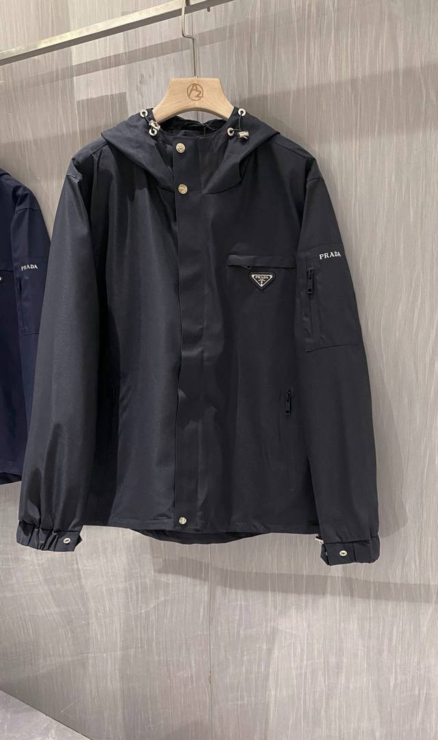 普拉达 2025早秋新款原单男士连帽风衣夹克外套 官网同步售卖 爆款 高版本 时尚百搭 胸前绣三角Logo标设计 采用原版进口100%聚酯纤维记忆面料手感柔软细