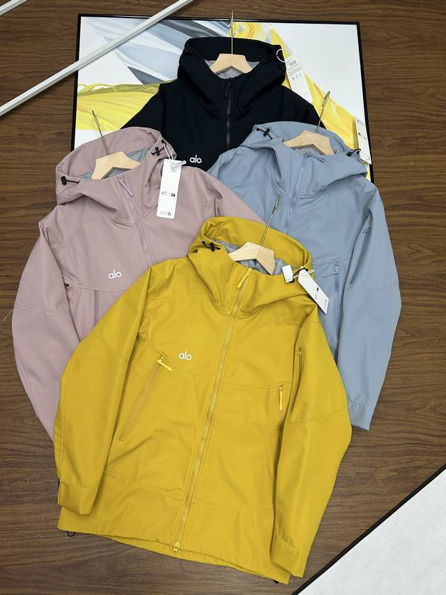 Alo情侣款冲锋衣Alo户外山系工装风连帽冲锋外套 这款软壳冲锋衣采用高品质的面料具有出色的防风性能能有效抵挡户外的强风侵袭为你提供温暖的防护。同时它的防水功能