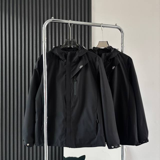 Alo 户外休闲系工装风连帽冲锋衣夹克外套 这款软壳冲锋衣采用高品质的面料，具有出色的防风性能，能有效抵挡户外的强风侵袭，为你提温暖的防护。同时，它的防水功能也