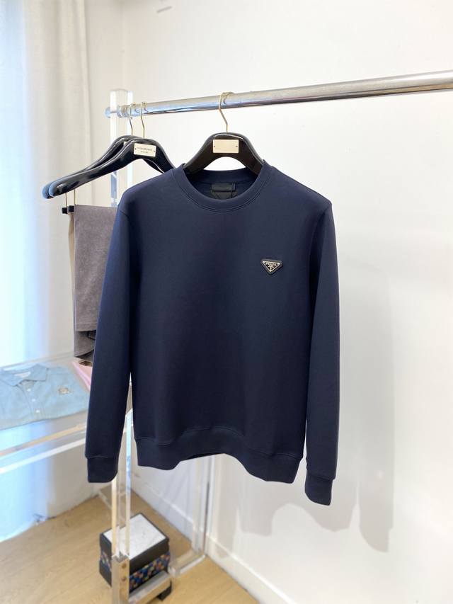 普拉达、2025新品卫衣，帅气时尚，简约百搭款。胸前五金装饰三角标Logo，面料棉 不仅挺括，保持潮流的廓形，又穿着舒适，纱织更细腻，码数M-2Xl