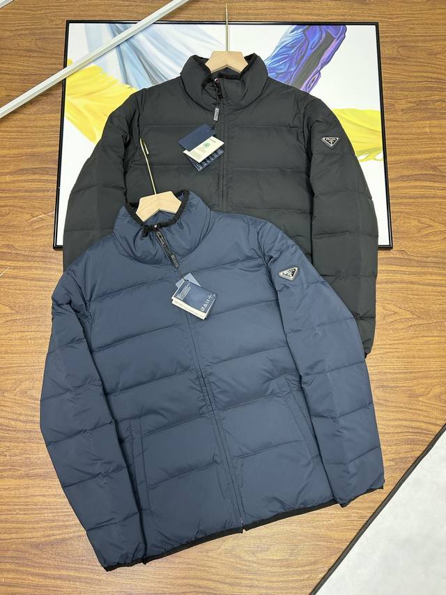 普拉达立领款羽绒服prada 普拉达 金属标 再生尼龙 男士加厚保暖羽绒服外套。面料选用客供的再生尼龙，非常符合当下的环保理念。经典的商务休闲风格简约干练。搭配