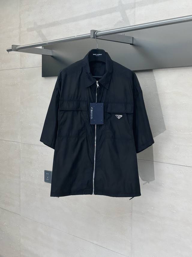 prad* 普拉达 尼龙双口袋短袖衬衫 采用轻盈的Re-Nylon环保材质打造，兼具耐用性与环保理念。Oversize版型设计呈现现代极简风格，方正廓形搭配平直