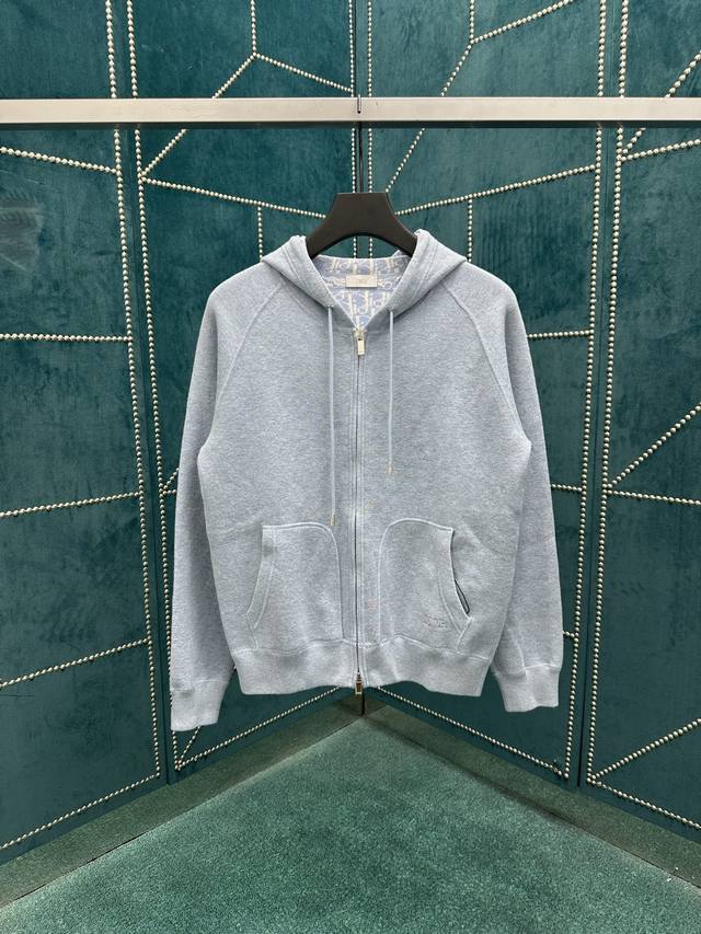 迪奥 25Ss新款连帽运动夹克将经典高订气质融入基本款单品。采用蓝色棉质混纺针织面料精心制作，搭配风帽、拉链和插肩袖设计。正面饰以 Dior 刺绣，内侧通体饰以