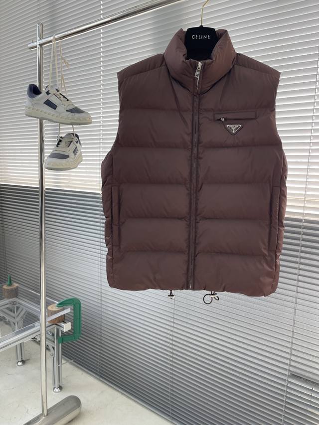 prad 25Fw新款夹棉三角微标马甲，此款Re-Nylon背心线条经典，风格百搭，散发运动魅力。饰有涂珐琅金属三角形徽标。立领式设计拉链开合，嵌线拉链口袋，弹