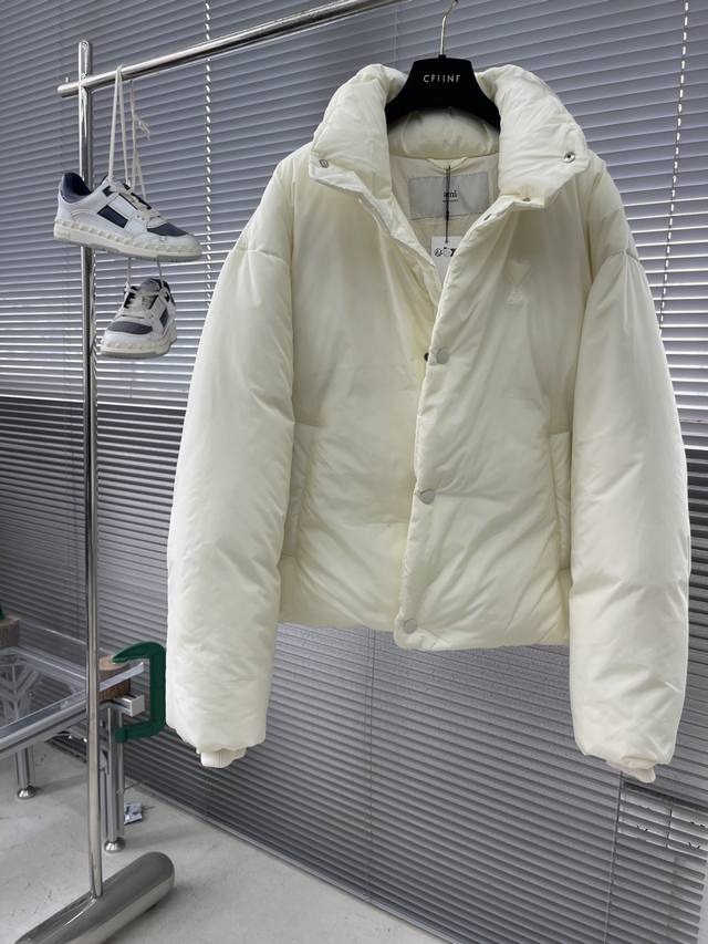 Ami 爱心垫衬绣羽绒外套 选用100%聚酯纤维编织而成的塔夫绸面料。采用经纬线平纹组织，编织得非常紧密，使得面料表面极其光滑、平整，自带一种“骨感”和挺括度，