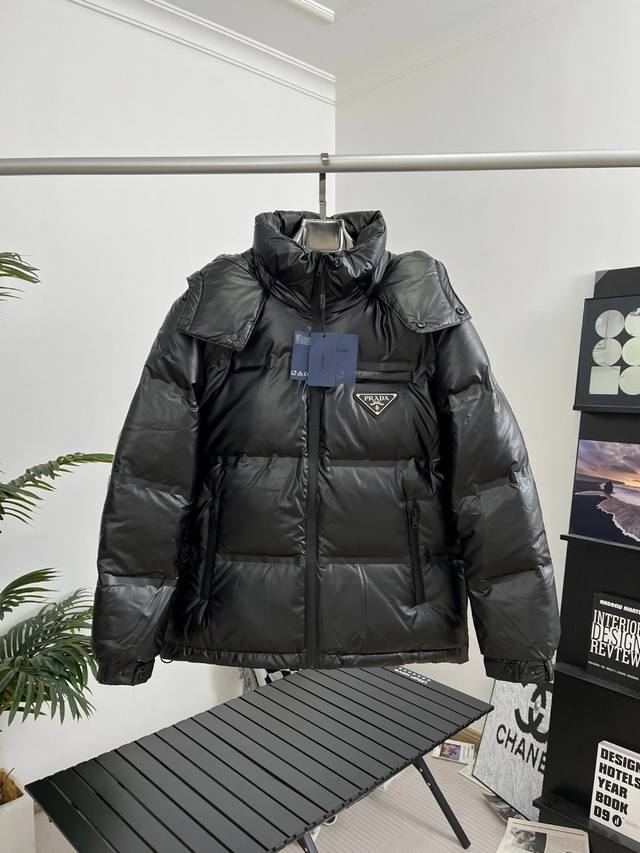 prada｜普拉达三角标科技布短款连帽羽绒服 颜色：黑色 尺码：48-56 描述： 该款短款派克羽绒采用 亮皮面料制成，服装满载功能性细节，确保温暖呵护。设有可