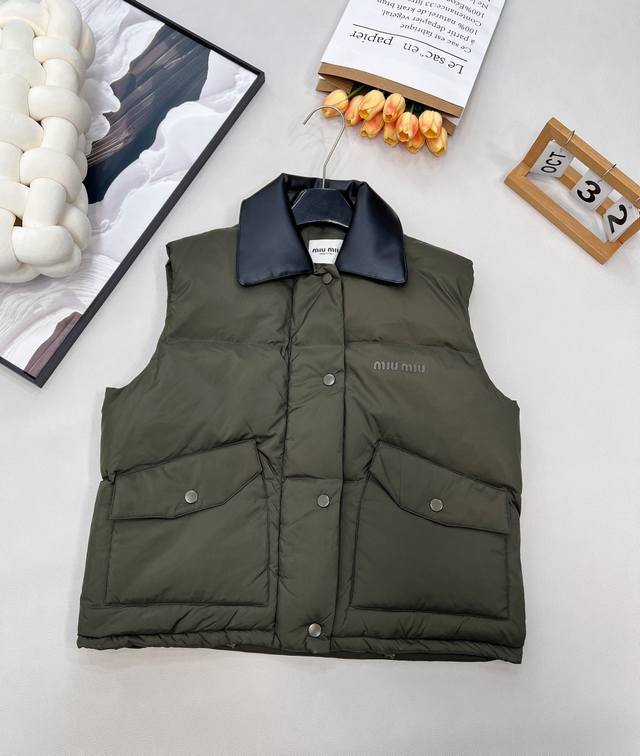 Miumiu25Fw秋冬新款撞色真牛皮翻领无袖羽绒服马甲丨独家Yb开发！高版出品！撞色真牛皮翻领是视觉焦点，深棕皮革的硬朗质感与羽绒面料的蓬松柔软形成强烈对比，