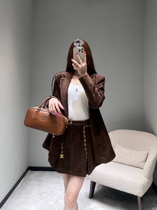 Celi*E 2025Fw新款系列系列 Ce西装短裙套装深棕色灯芯绒面料，采用经典的翻驳领设计，两粒金色纽扣精致亮眼，利落的剪裁；短裙点缀的金色链条极具设计感，