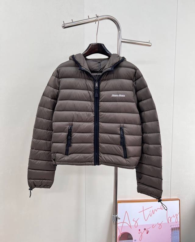 Miumiu2025新款连帽亮面拉链羽绒服，定制Yb防风防水尼龙材质 白鹅绒填充内里 整件轻盈保暖 连帽翻领剪裁 以撞色包边装饰帽领和前襟拉链作细节亮点 胸前单