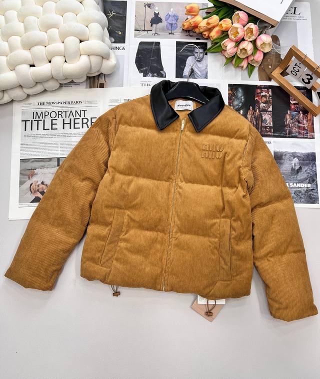 Miumiu 暖色灯芯绒皮翻领拉链羽绒服， 采用灯芯绒面料，手感柔软细腻，保暖性良好。同时，灯芯绒的表面纹路清晰分明，分布均匀、规则。灯芯绒原料以棉为主，全棉纺