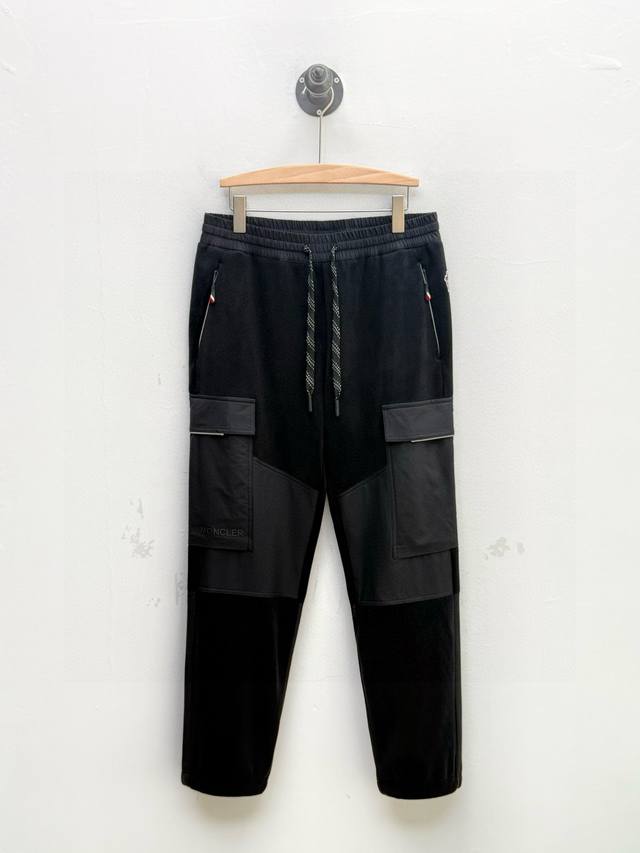 Mon 尼龙拼摇粒绒徽标卫裤、贸易公司订单 秋冬系列 这款卫裤采用经典的直筒微锥版型，两侧饰有工装风琴袋，其中右侧裤袋上点缀有品牌Logo，字母边缘整齐，做工考