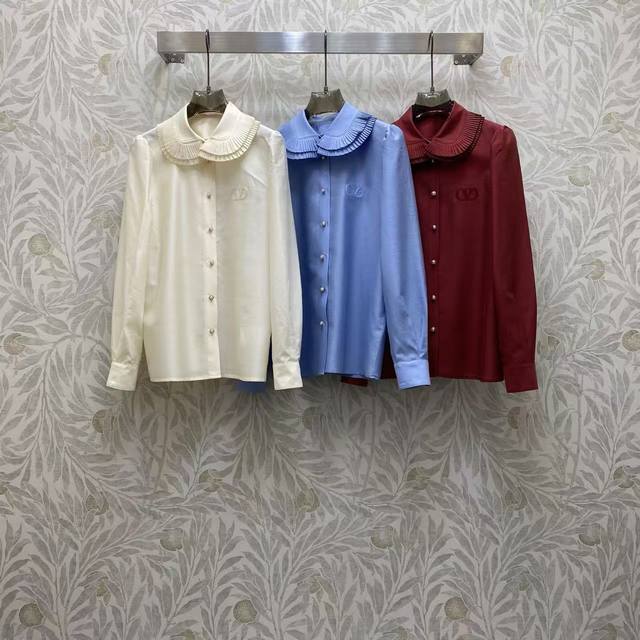 Va2026 Sp 精品衬衫 这衬衫采用温柔娃娃领+精致褶皱设计，搭配珍珠纽扣与低调徽标刺绣，奶白 浅蓝 酒红三色适配多场景，质感优雅又减龄。 颜色:白，浅蓝，