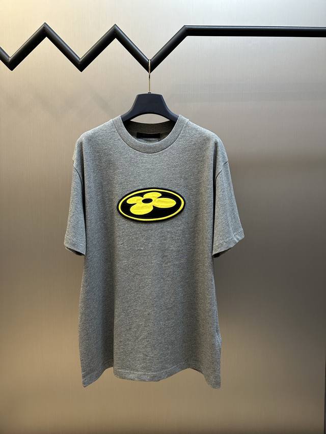 Lv 贴饰章仔刺绣短袖 本款T恤取材柔软棉布，以2025秋冬秀场的风尚元素点亮日常造型。正面Lv Flower丝缎贴饰融入大胆笔触，与后部Vuitton刺绣标识