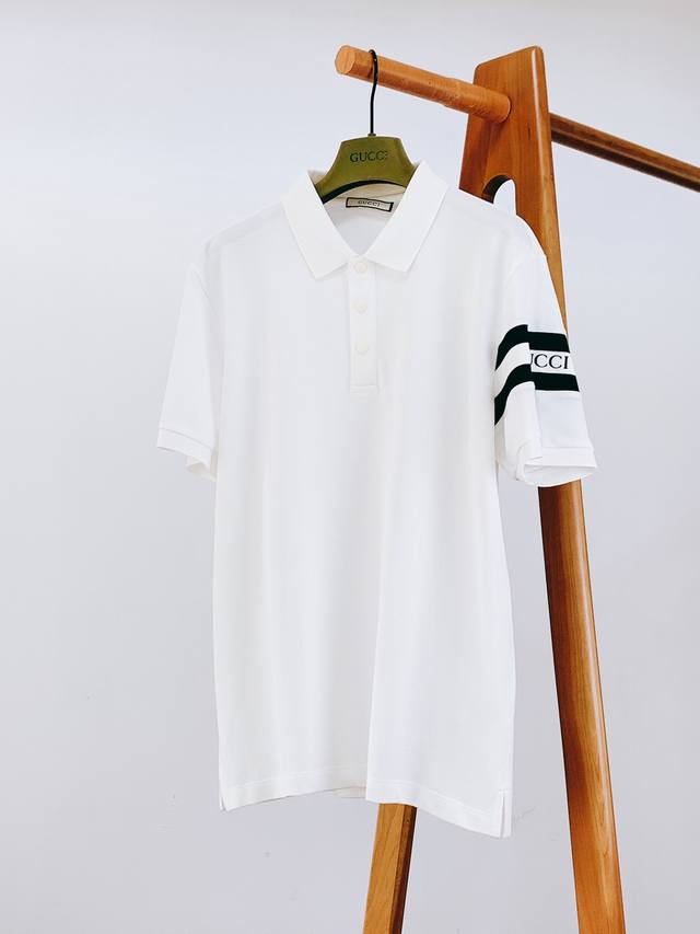 Gucci 古驰 2025Ss春夏新品 休闲商务 polo 衫，以利落版型开启简约新章，每处细节都藏着品牌对质感的执着： 左臂三条白杠贯穿 “Gucc*” 字母