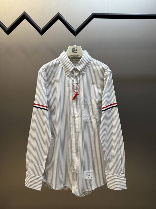 Thom Browne 织带条纹衬衫 定制全棉色织条纹天然织料，低调深灰邂逅经典条纹，独具辨识度的标志性条纹罗缎标饰臂环，Tb独特印记标签点缀于下摆处，织带为缀