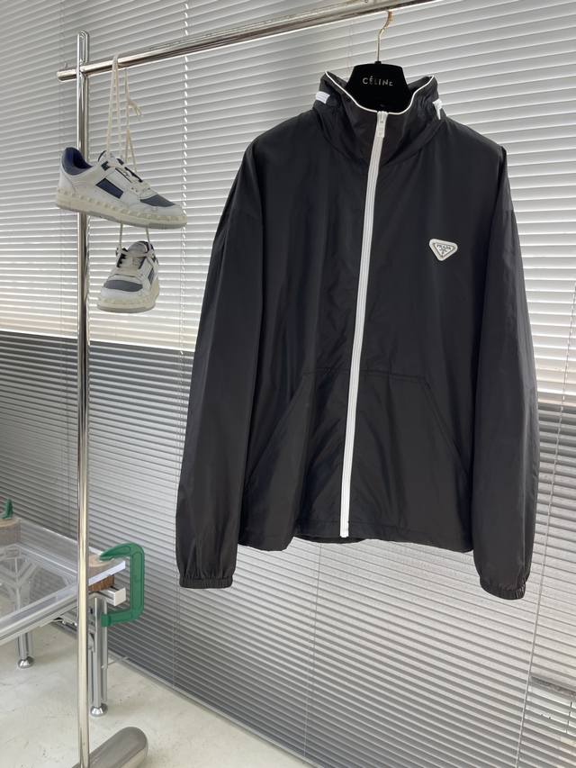 prad 25Ss新款立领再生尼龙夹克 这款再生尼龙夹克融合运动风设计与时尚风格，功能性廓形别具个性，撞色拉链平添趣致图形细节，帽子可收纳实现一衣多穿，即做立领