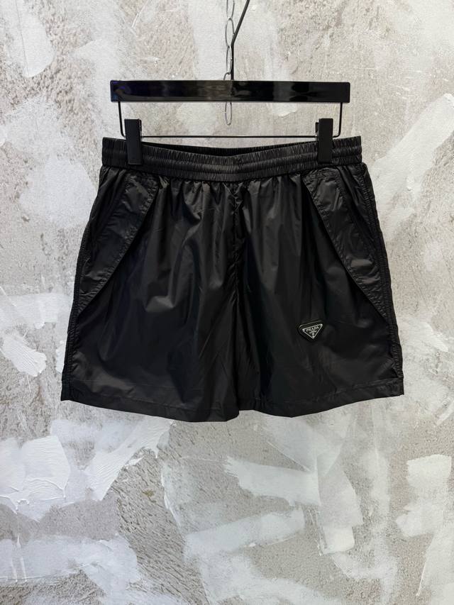 prad三角标拉链遮挡口袋尼龙短裤 定制再生幻纶尼龙织物 清爽透气 舒适贴肤 以深邃的黑为主色调 纯粹而深邃 标志性prad三角标点缀于裤身 尺码Size :
