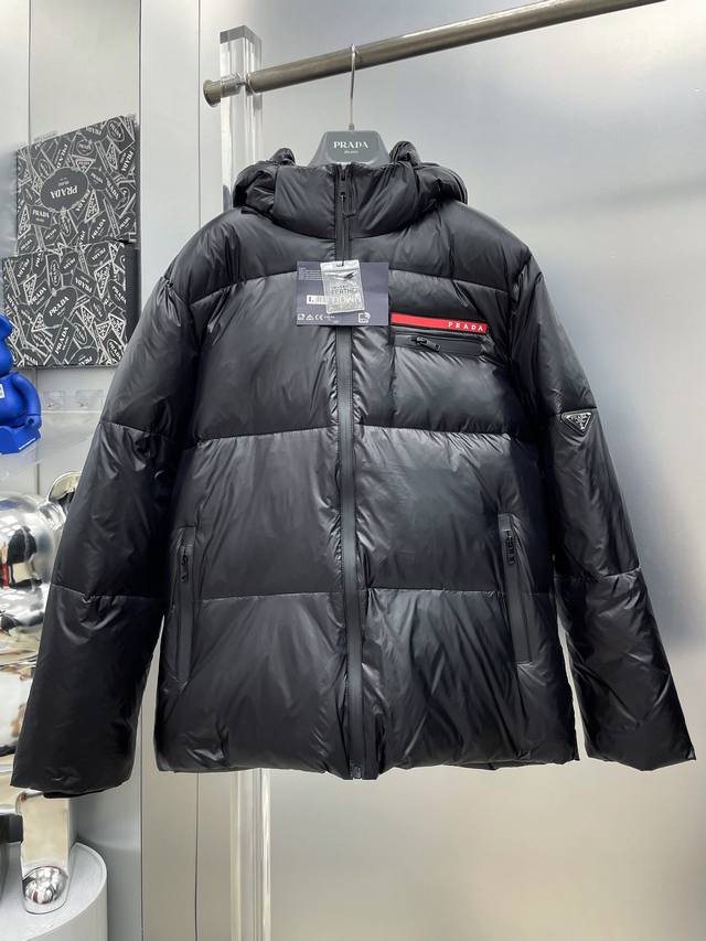 pra*普拉达 2025秋冬新款红标拉链口袋Logo羽绒服连帽外套 D全部90绒的三标齐全带着经典的Logo组合搭配，第一眼看到就是满满的视觉冲击，保暖性能更出