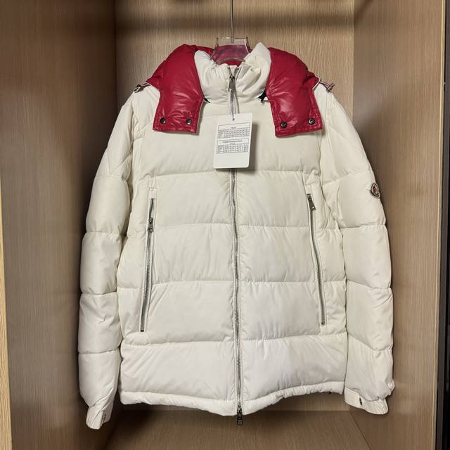 Moncler蒙口米白色 帽子带有红色拼接设计 和黑色款式，都具备可脱卸式连帽设计，拉链、口袋等细节处的红色元素为整体造型增添了设计感，符合该品牌既注重功能性又