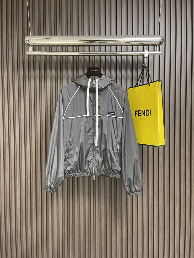 Miu Miu 拉链风帽夹克，定制冷萃智孔纤维尼龙精纺布 轻薄细腻 舒适贴肤 以经典黑为主色调 深達与高贵的极致融合 醒目的Miumiu徽标贴饰点缀于胸前 展现