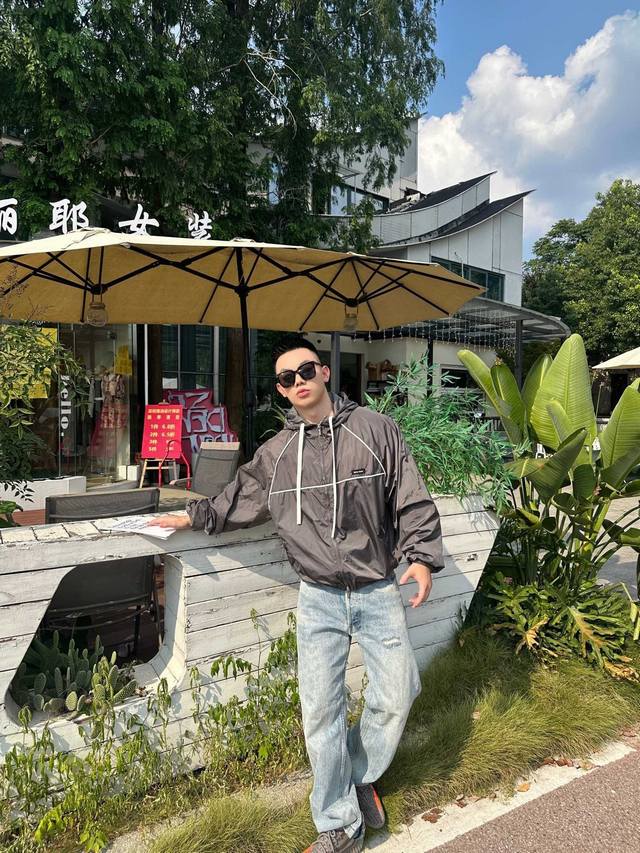 Miumiu 拉链风帽夹克 定制冷萃智孔纤维尼龙精纺布 轻薄细腻 舒适贴肤 以经典黑为主色调 深達与高贵的极致融合 醒目的Miumiu徽标贴饰点缀于胸前 展现出